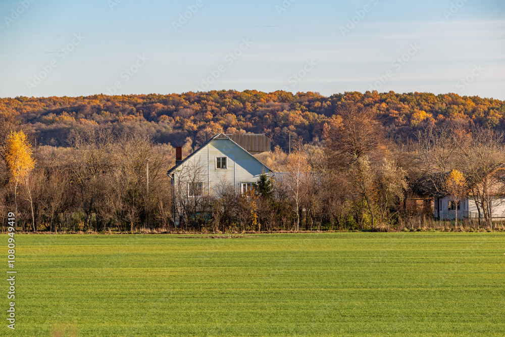 Obraz premium Rural house on the background of the nature of the autumn forest