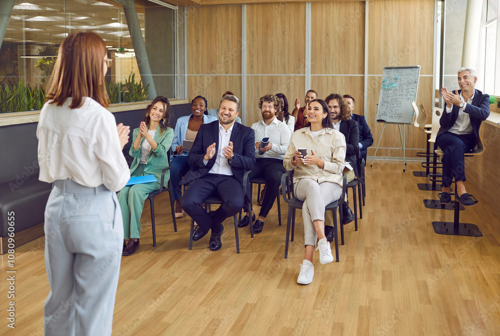 Happy audience applauding woman speaker after her presentation at business meeting or seminar. Group of cheerful diverse multiethnic people sitting in office, clapping hands and smiling Happy audience applauding woman speaker after her presentation at business meeting or seminar. Group of cheerful diverse multiethnic people sitting in office, clapping hands and smiling