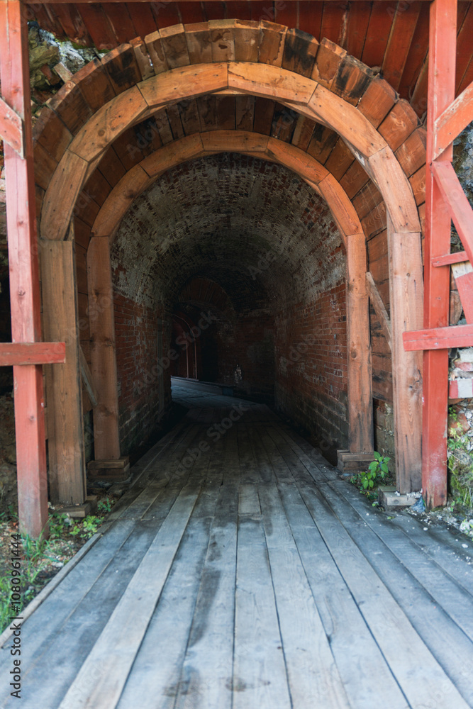 Obraz premium Entrance to dark wooden and stone tunnel in historic fortress