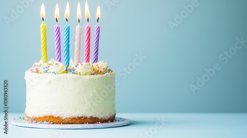 Birthday cake with five lit candles and colorful sprinkles