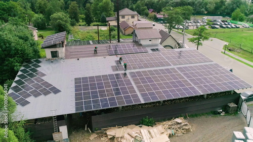 Workers installing PV solar panels on the roof of a house,which converts solar energy into electric energy. Concept of work. Workers in special outfit walk and talk about sunny cells installation. photo