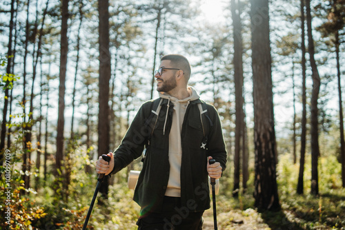 Young caucasian man hiking or trekking through the forest 