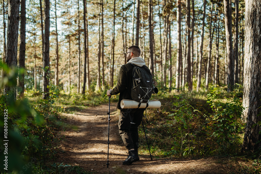 Young caucasian man hiking or trekking through the forest Young caucasian man hiking or trekking through the forest