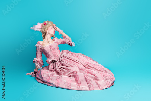 Photo of charming lovely lady princess marie antoinette wear pompous pink ruches gown sit floor faint isolated on blue color background photo