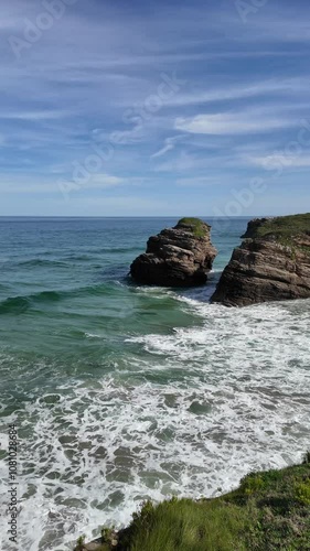 Expansive beach scene at Playa de las Catedrales in Lugo, Galicia, featuring striking rocky cliffs and gentle ocean waves.
