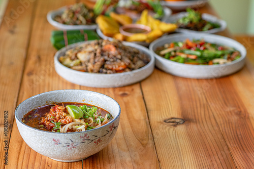 Khao Soi Chiang Tung is served in a bowl with sticky rice noodles and a flavorful soup that is Chiang Tung style. The delicious Khao Soi Chiang Tung is a popular noodle dish among Tai Yai people. photo