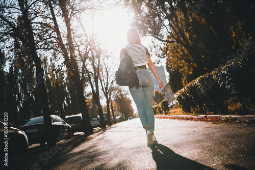 Full length photo of attractive young cheerful lady walking back view wear khaki garment tied shoulders sweater having fun outside outdoors photo