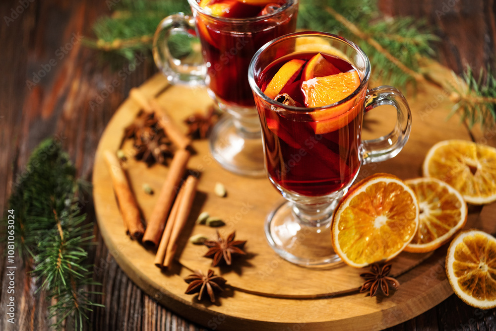 Hot mulled wine or alcohol grog with oranges and spices of cinnamon in a glasses on wooden table. A traditional warming drink for the autumn winter season. Hot mulled wine or alcohol grog with oranges and spices of cinnamon in a glasses on wooden table. A traditional warming drink for the autumn winter season.