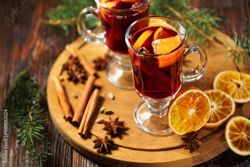 Hot mulled wine or alcohol grog with oranges and spices of cinnamon in a glasses on wooden table. A traditional warming drink for the autumn winter season.