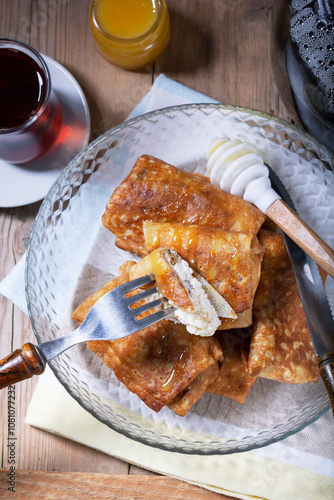 Obraz na płótnie Pancakes with cottage cheese and raisin filling, served with honey and black tea. Traditional treat for Maslenitsa or Carnival. w salonie