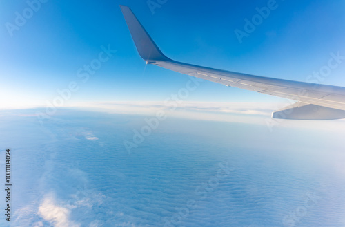 View from the airplane window at a beautiful cloudy sky and the airplane wing