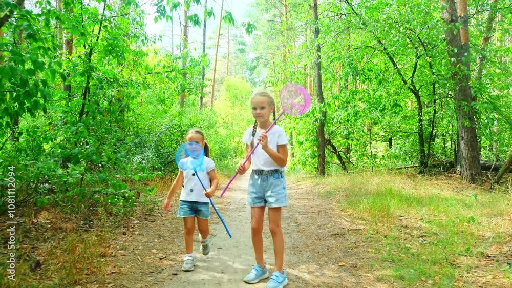 Two little sisters catching butterflies and bugs with their scoop-nets on beautiful sunny summer day Two little sisters catching butterflies and bugs with their scoop-nets on beautiful sunny summer day