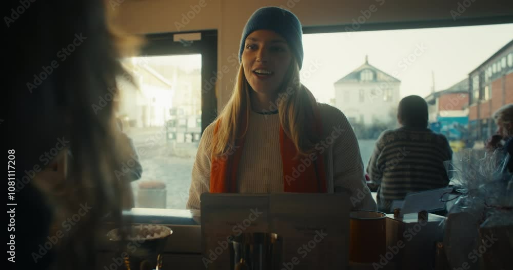 A female customer and woman barista or cafe owner have a friendly chat and interaction over the counter. Staff employee and customer ordering drinks, get served tea in scandinavian cafe A female customer and woman barista or cafe owner have a friendly chat and interaction over the counter. Staff employee and customer ordering drinks, get served tea in scandinavian cafe