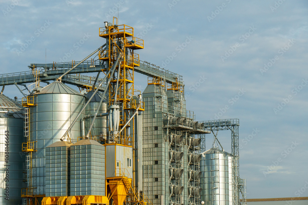 silver silos on agro manufacturing plant for processing drying cleaning and storage of agricultural products, flour, cereals and grain. Large iron barrels of grain. Granary elevator silver silos on agro manufacturing plant for processing drying cleaning and storage of agricultural products, flour, cereals and grain. Large iron barrels of grain. Granary elevator