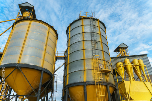 silver silos on agro manufacturing plant for processing drying cleaning and storage of agricultural products, flour, cereals and grain. Large iron barrels of grain. Granary elevator photo