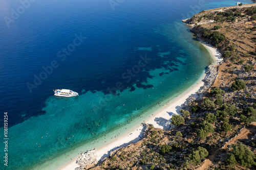 Drone Aerial view of tourists enjoying summer on a Greek isolated tropical beach with turquoise water.