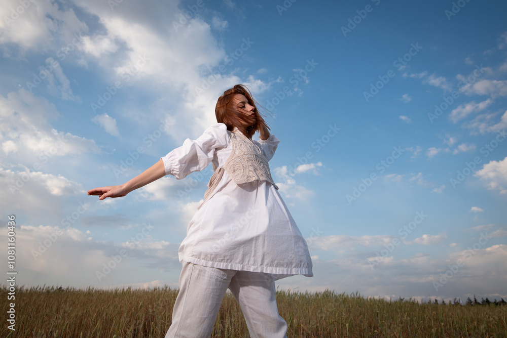 Young woman wearing white dress dancing outdoors against blue cloudy sky. Young woman wearing white dress dancing outdoors against blue cloudy sky.