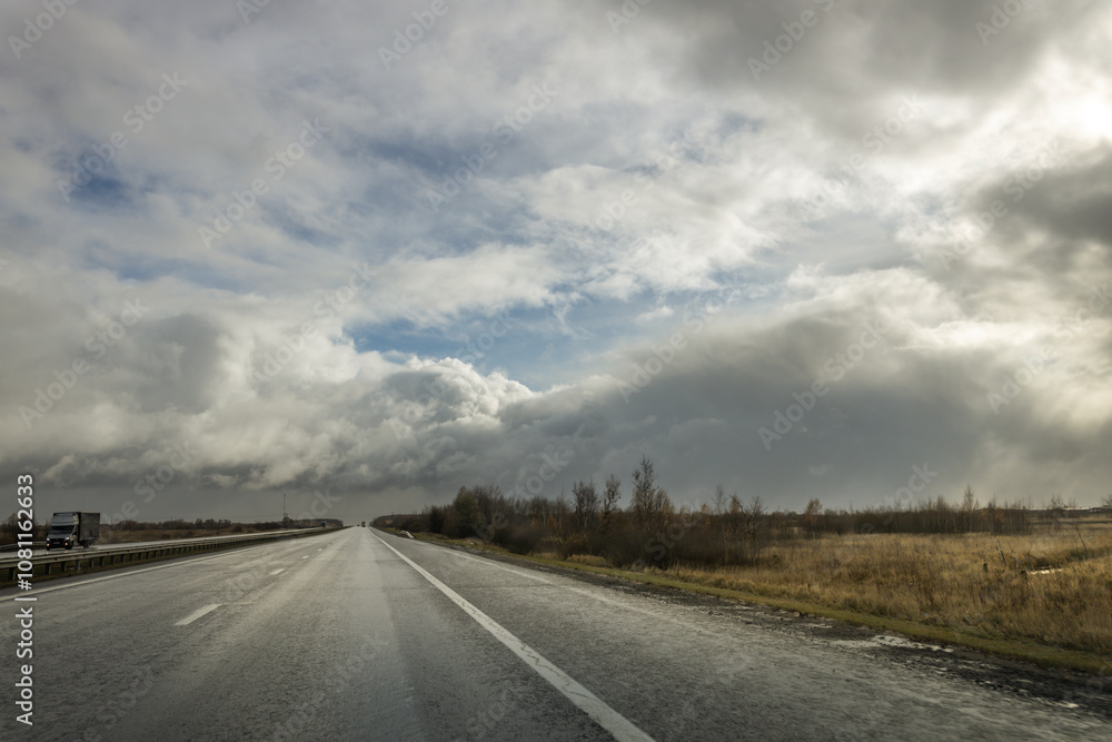 Fototapeta premium A road with a few cars on it and a cloudy sky