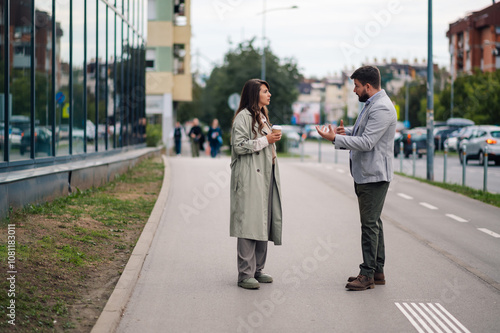 Business people having conversation about work on city street during coffee break