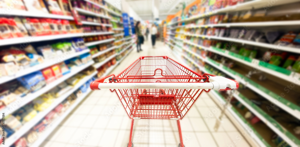 Fototapeta premium Pusty koszyk, wózek sklepowy w supermarkecie, rozmazane tło, wnętrze sklepu, supermarketu, wózek na zakupy, półki sklepowe z produktami. Hipermarket. Baner, miejsce na tekst.