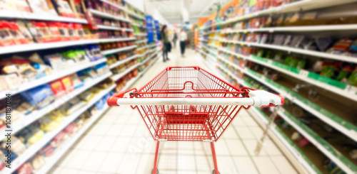 Pusty koszyk, wózek sklepowy w supermarkecie, rozmazane tło, wnętrze sklepu, supermarketu, wózek na zakupy, półki sklepowe z produktami. Hipermarket. Baner, miejsce na tekst.