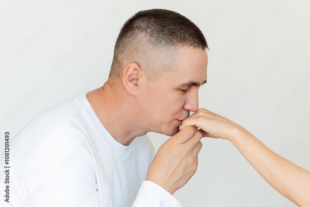 A young man in white clothes gently kissing a young woman's hand while holding her hand A young man in white clothes gently kissing a young woman's hand while holding her hand