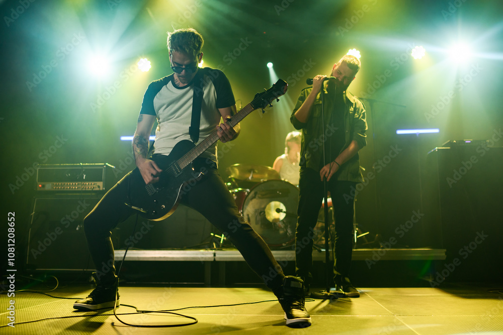 Fototapeta premium Rock band performing live on stage with energetic guitarist