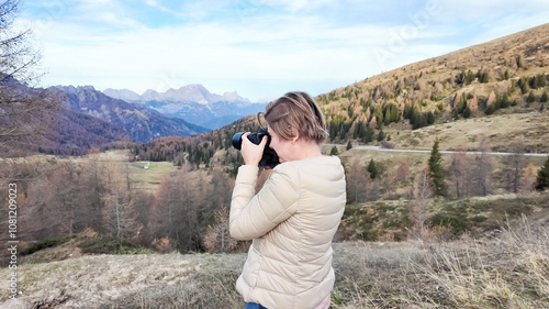 A Caucasian woman captures stunning autumnal mountain landscapes with her camera, emphasizing the beauty of nature photography during fall