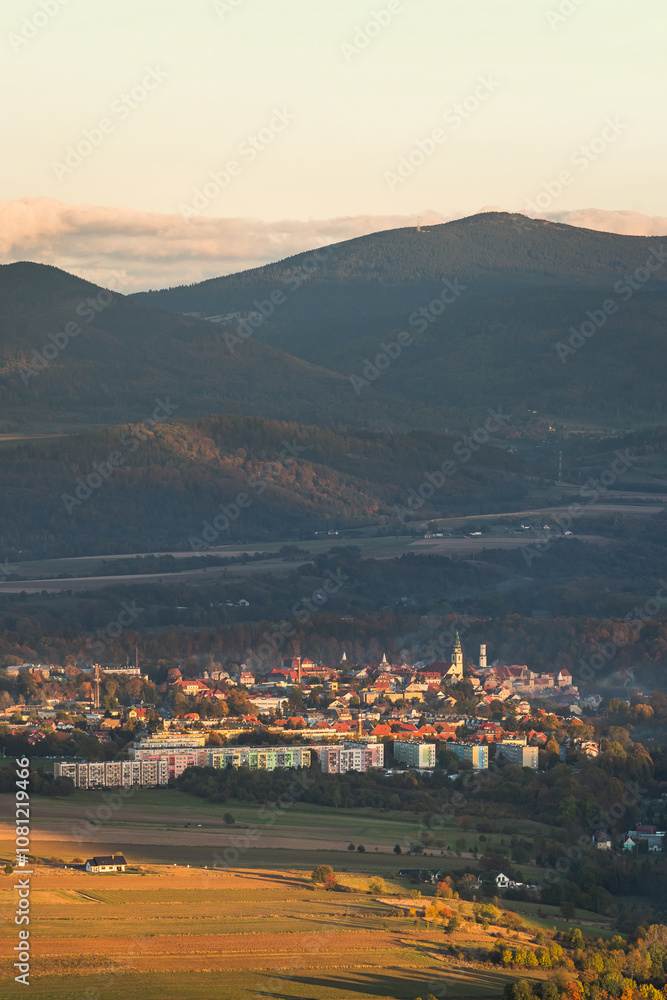 Bystrzyca Klodzka, a small town in a mountain valley, a view of the city's buildings from the hiking trail in the Bystrzyckie Mountains. Landscape in the evening.
