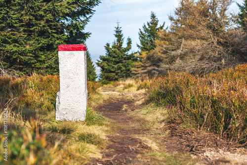 Karkonosze Mountains, Western Sudetes, Polish-Czech border post on a mountain hiking trail leading through the forest along the state border.