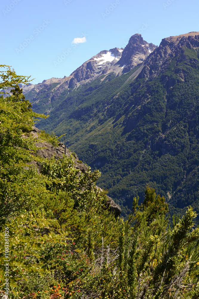 Beautiful close up of snowy rocky mountains and forest with green trees part of a challenging trekking trail that connects Natacion Lake and Cajon del Azul landmarks in El Bolson, Rio Negro, Argentina