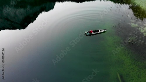 The fisherman in the boat on the green lake