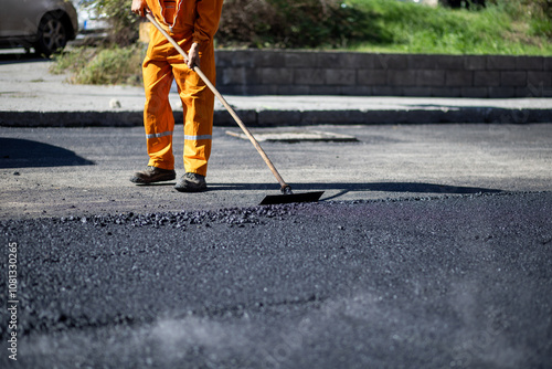 Foto Road worker applying fresh asphalt on a sunny day in a city street, focusing on