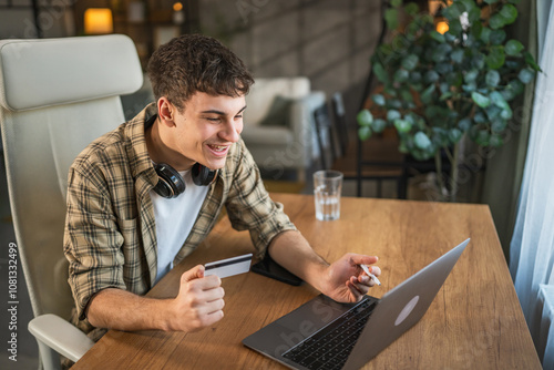 Fotografie Young caucasian man shopping online with credit bank card on laptop