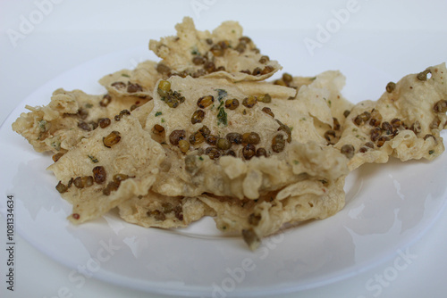 Traditional crackers with mung bean sprinkles from Indonesia, called Rempeyek Kacang Hijau. On white plate, isolated on white background photo