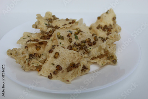 Traditional crackers with mung bean sprinkles from Indonesia, called Rempeyek Kacang Hijau. On white plate, isolated on white background photo