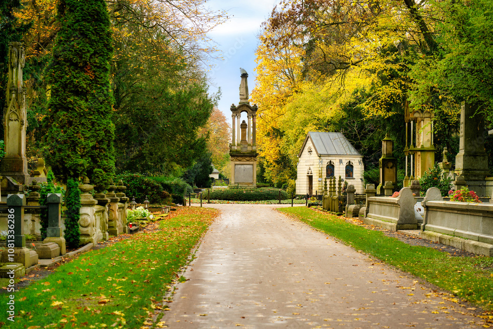 Fototapeta premium Autumn at the historic Melaten cemetery with a view of the central eagle column from the so-called million avenue
