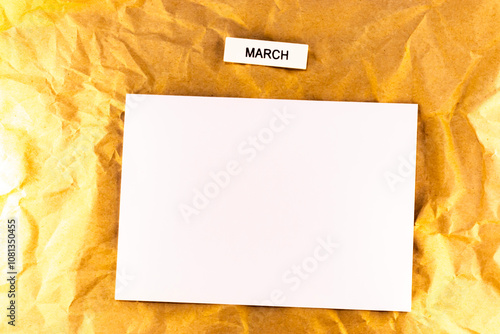 blank sheet of paper with a sheet of white paper with a yellow ribbon on a wooden table white list of plans or goal for meetings and events for the month march