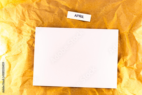 yellow blank paper on the wooden background, yellow flower white note of plans for meetings and events for the month april