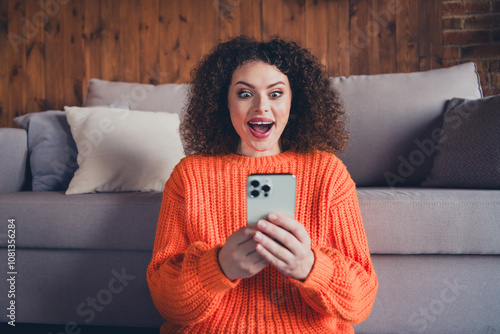 Portrait of nice young girl open mouth use smart phone wear orange sweater modern loft interior flat indoors photo