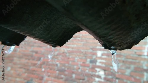 Heavy Rain Pouring Over a Corrugated Roof with Brick Wall Background