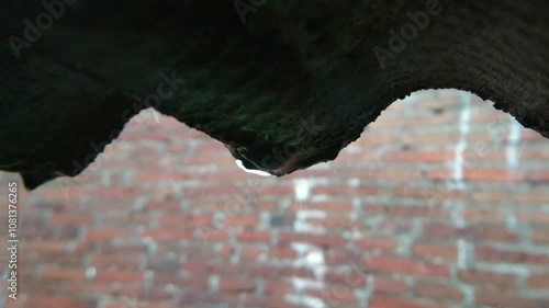 Heavy Rain Pouring Over a Corrugated Roof with Brick Wall Background