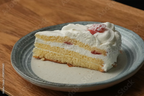 One small Japanese strawberry shortcake on a stylish Japanese plate on a wooden tray on a black cloth on a white table