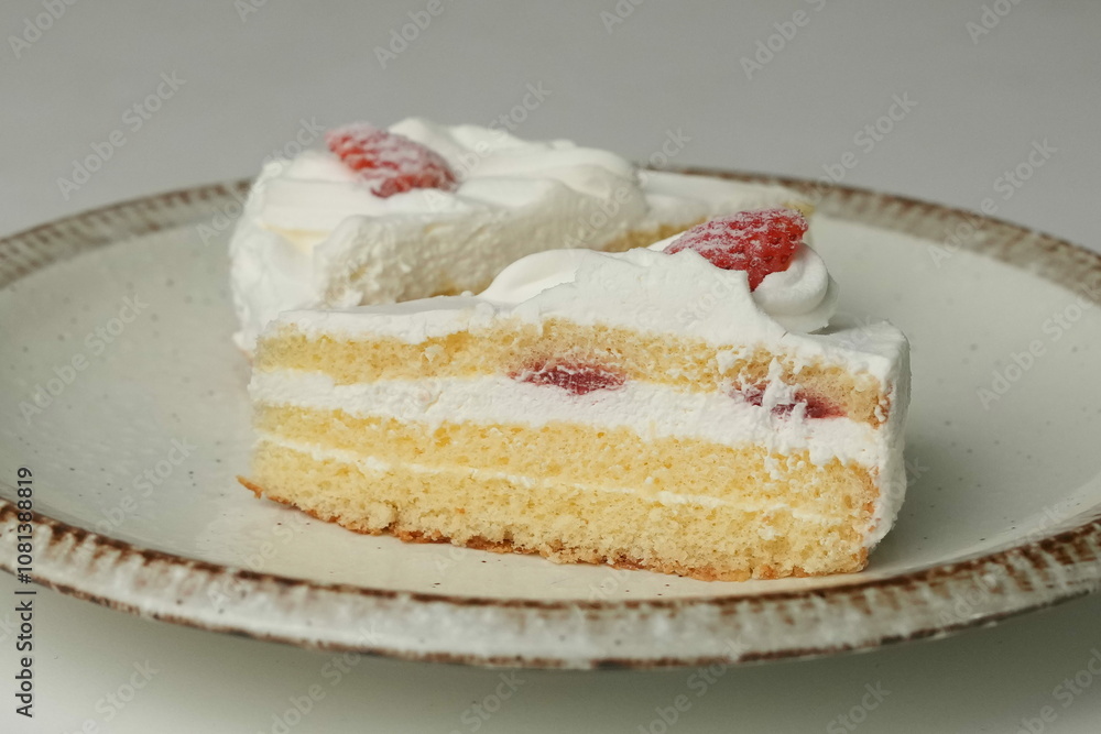 Two Japanese strawberry shortcakes on a stylish large plate on a white table Two Japanese strawberry shortcakes on a stylish large plate on a white table