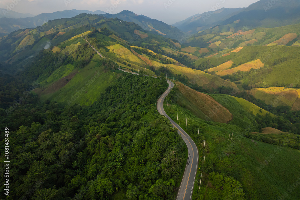 Aerial view of a road in the middle of the green forest and road curve construction up to mountain. Aerial view of a road in the middle of the green forest and road curve construction up to mountain.