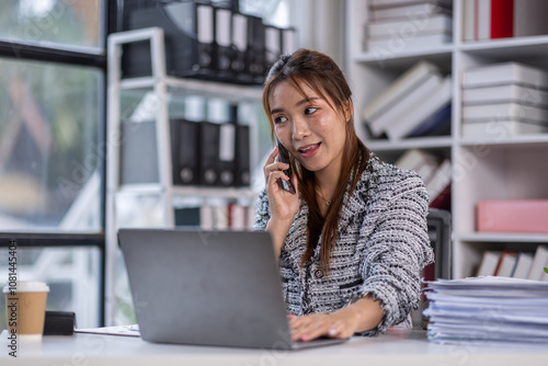 Asian business woman using calculator and laptop for doing math finance call phone at the office desk, tax, report, accounting, statistics, and analytical research concept.