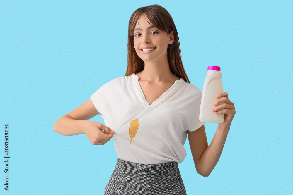 Young woman with detergent showing stain on her clothes against blue background Young woman with detergent showing stain on her clothes against blue background