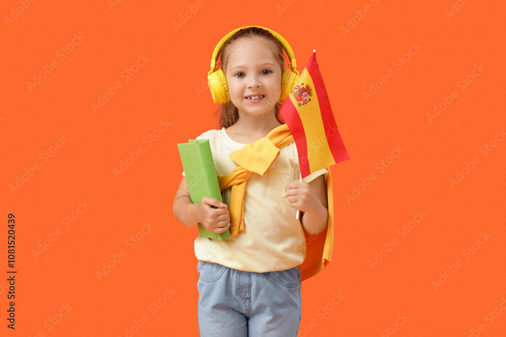 Little girl with Spanish flag and book on orange background