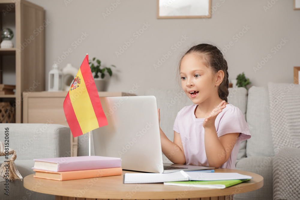 Little girl with laptop and books attending online Spanish language lesson at home Little girl with laptop and books attending online Spanish language lesson at home