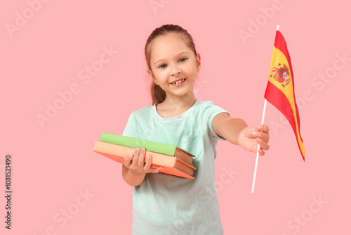 Little girl with books and Spanish flag on pink background